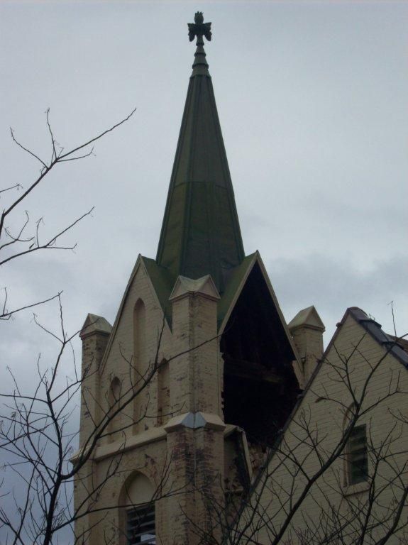 A church with a green steeple and a cross on top