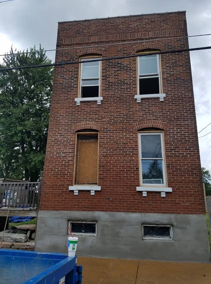 A tall brick building with a blue dumpster in front of it.