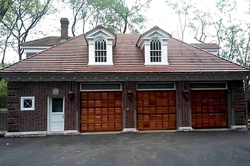 A large brick house with three wooden garage doors