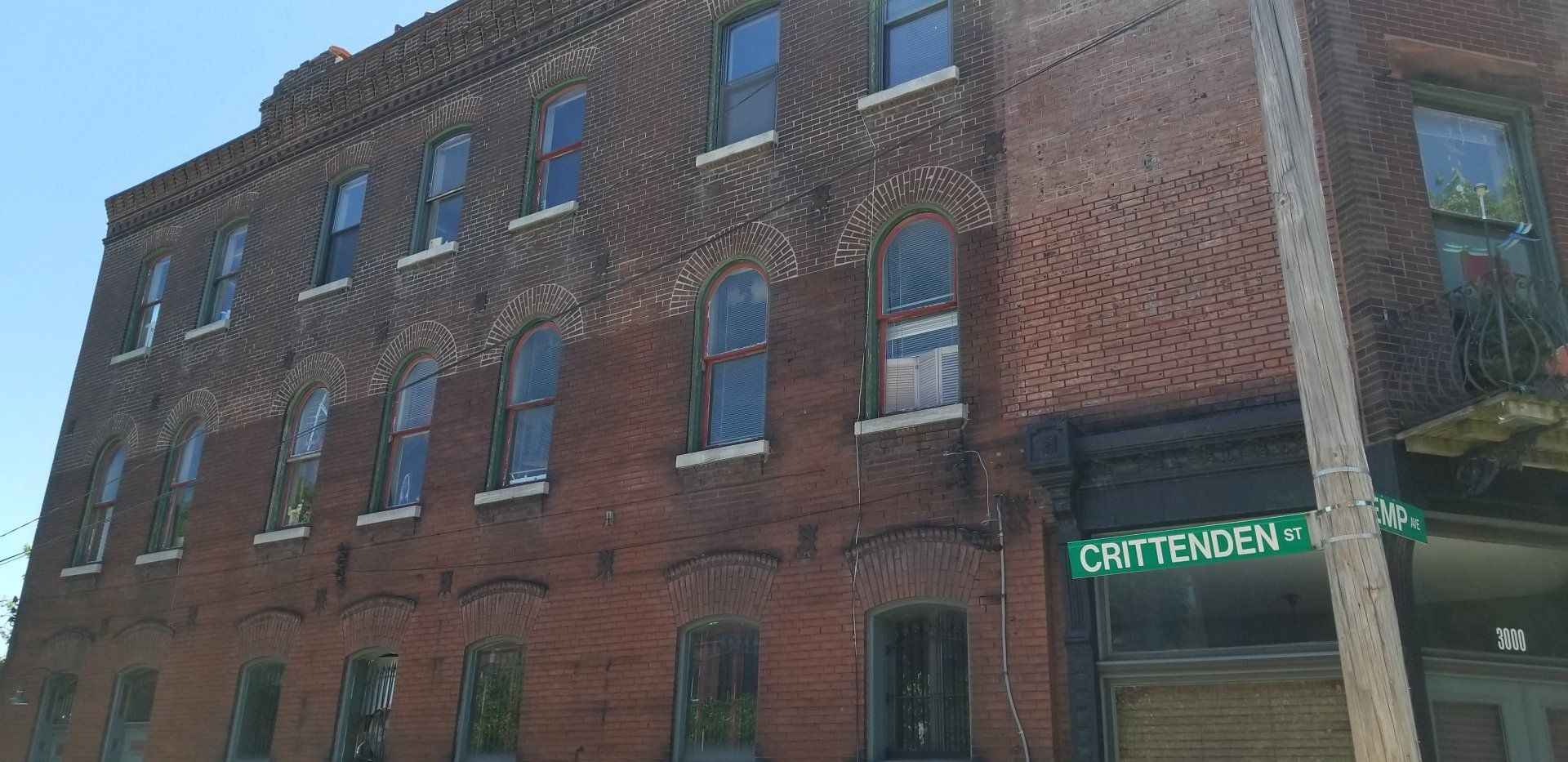 A large brick building with a green street sign in front of it.