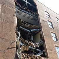 A large brick building with a balcony that has fallen down.