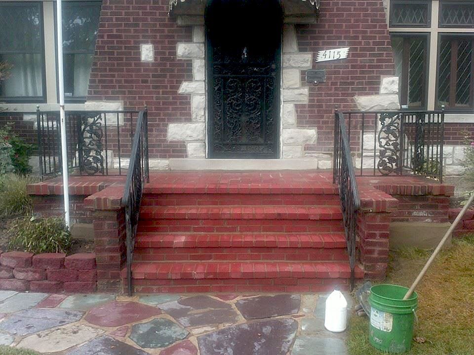 A brick house with a green bucket in front of it