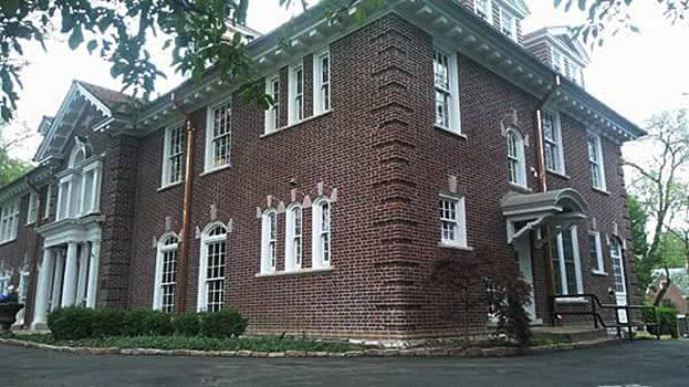 A large brick building with a lot of windows and a driveway in front of it.