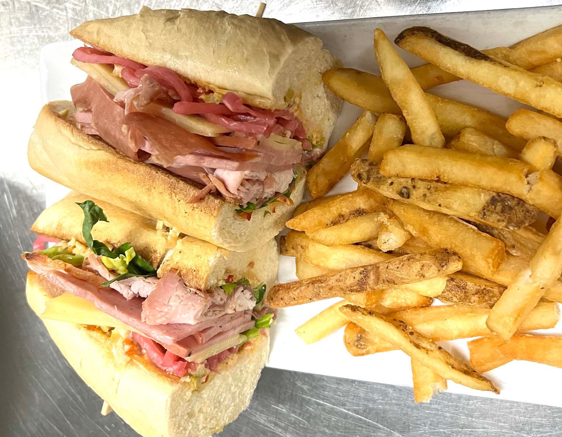 A sandwich and french fries are on a white plate.