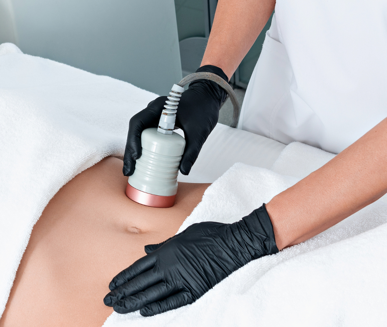 A woman is getting a cavitation treatment on her stomach.