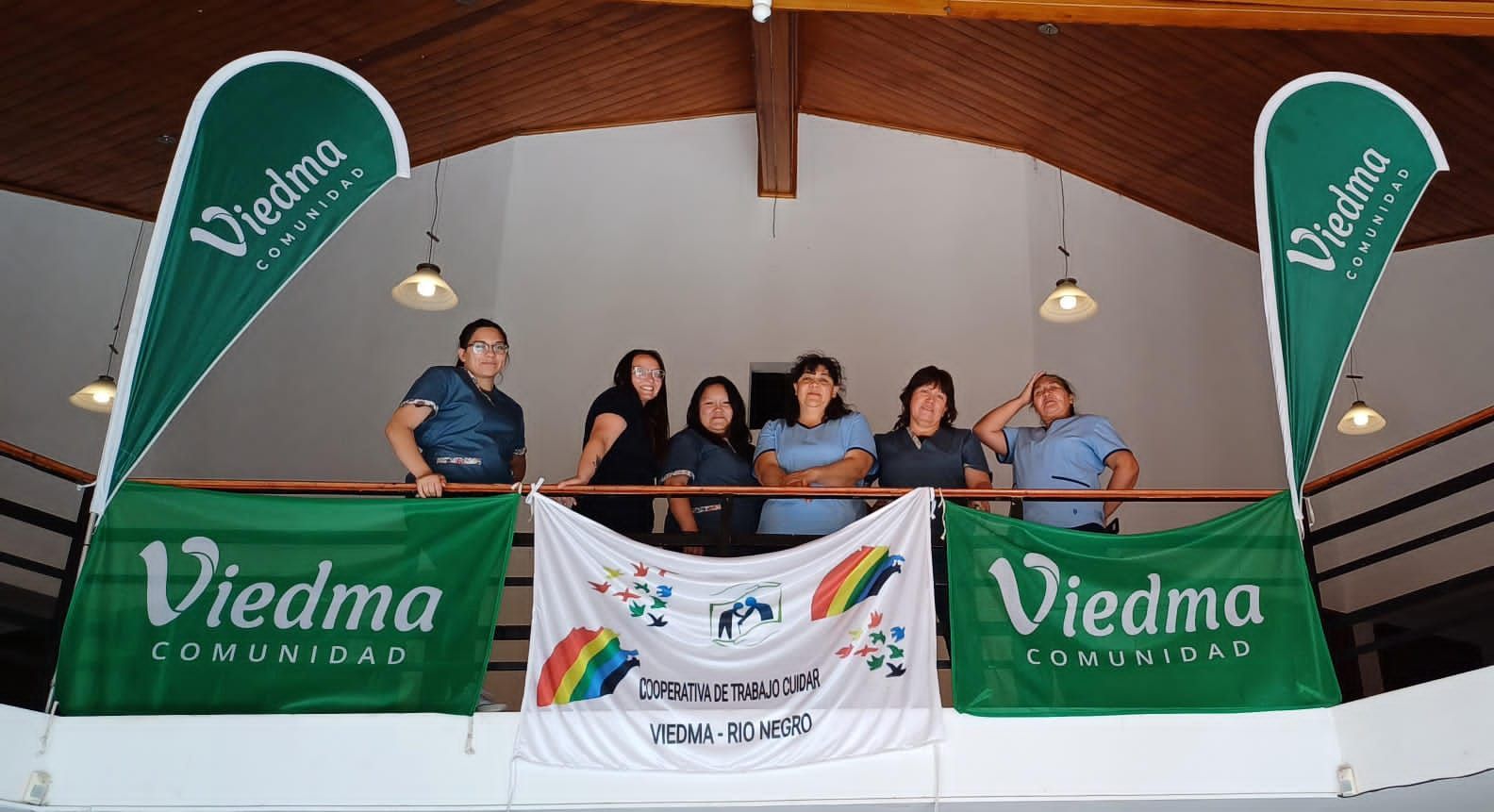 Un grupo de personas de pie en un balcón sosteniendo pancartas de Viedma.