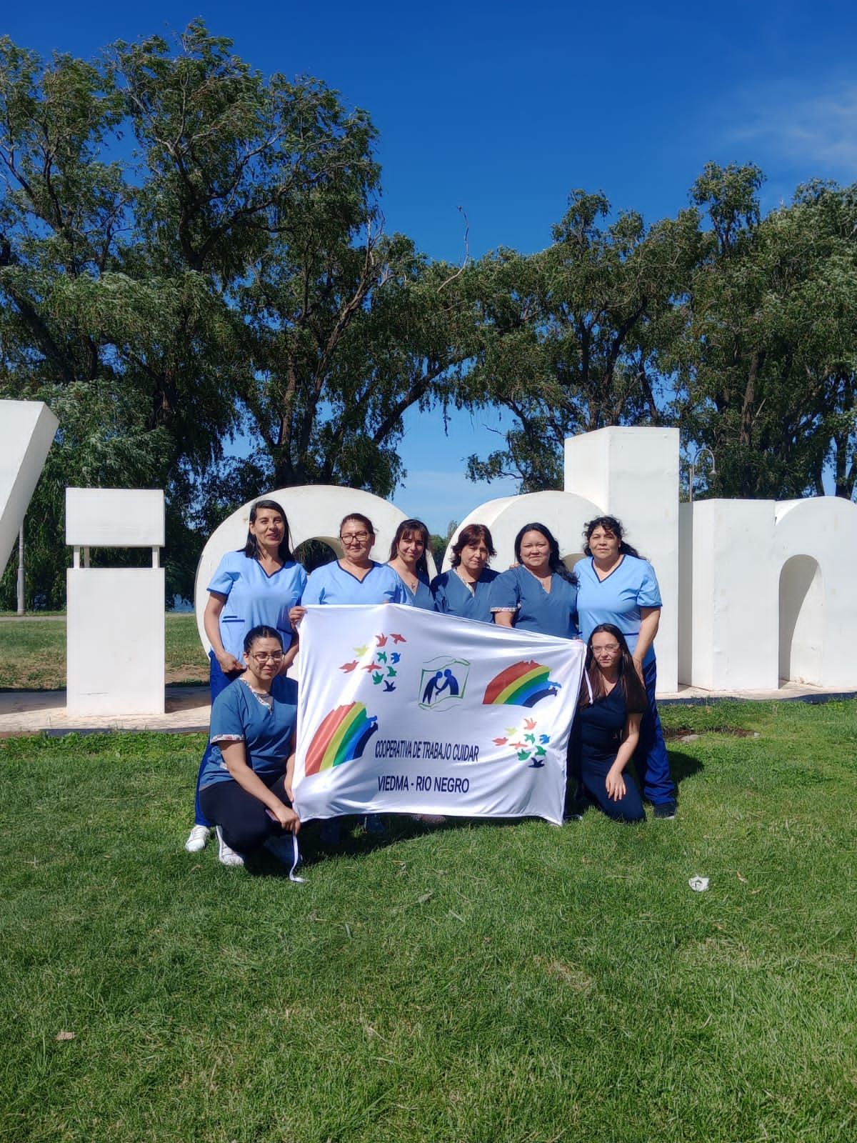 Un grupo de mujeres sosteniendo una bandera delante de un gran cartel.
