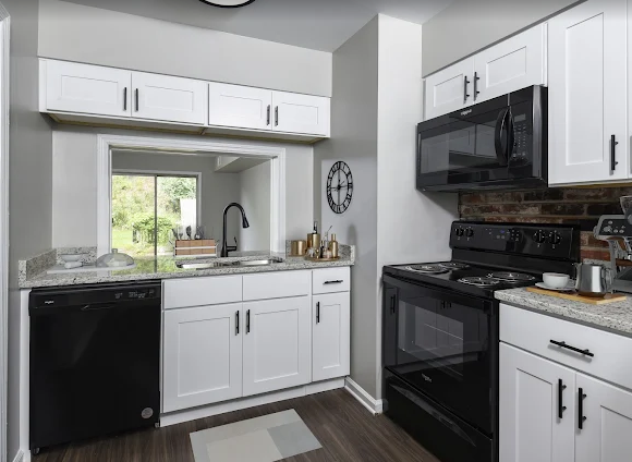 White kitchen with black appliances and granite countertops; includes a view-through window.