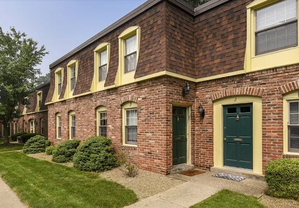 Row of brick townhomes with green doors and yellow trim.