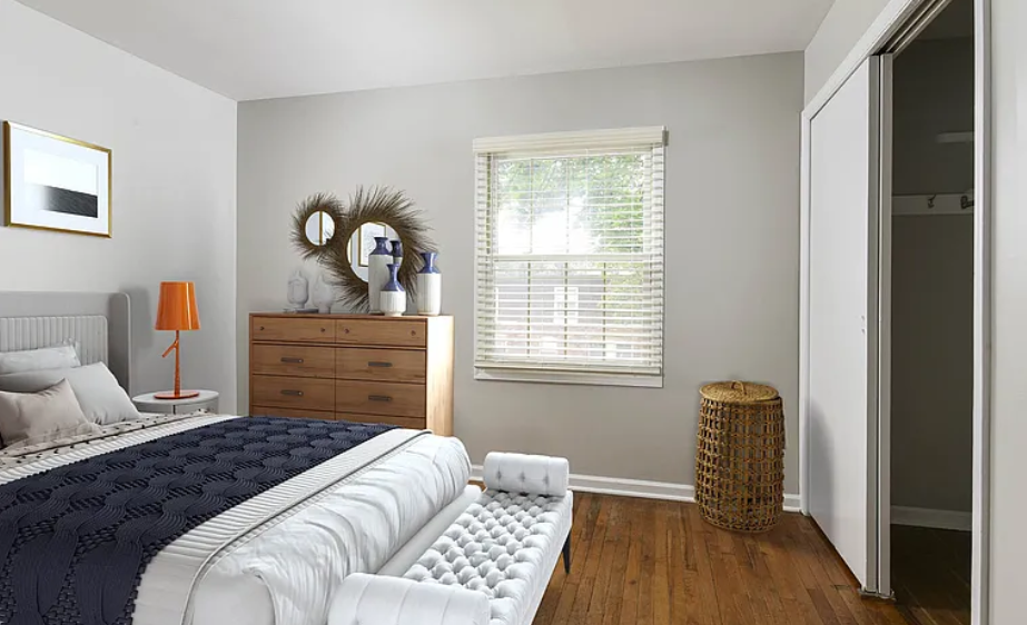 Bedroom with gray walls, wooden furniture, bed with navy blue cover, white bench, and closet.