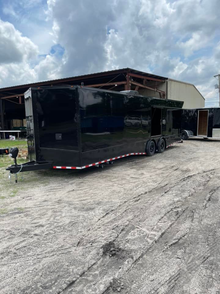 Black trailer parked outside a building on a cloudy day.