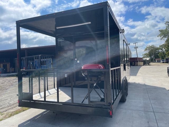 Black trailer with outdoor cooking space; grill and railing visible. Bright sky.