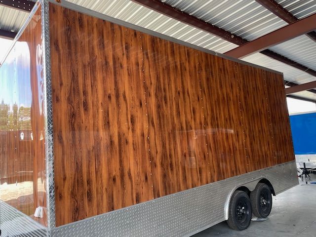 Cargo trailer with wood grain paneling and diamond plate base.