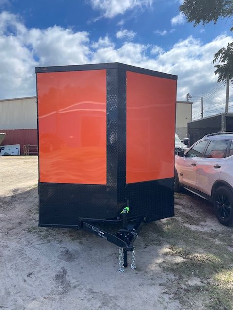 Orange and black enclosed trailer on a sunny day.