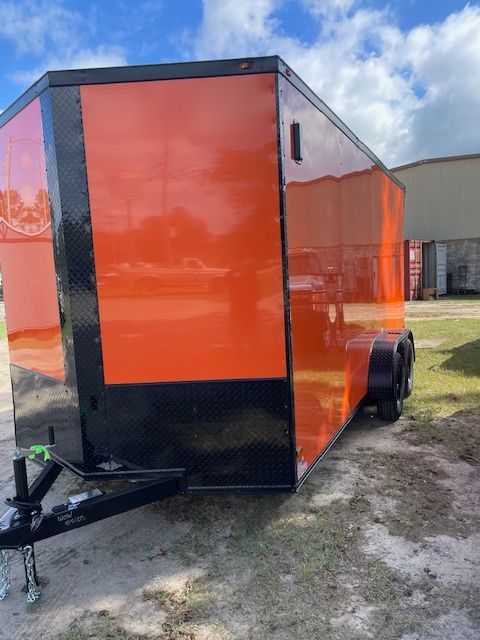 Orange and black enclosed trailer on grass.