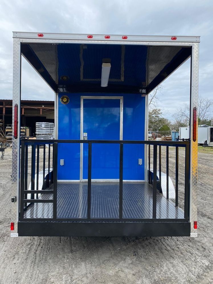 Rear view of a blue and silver trailer with a diamond plate floor and metal railing.