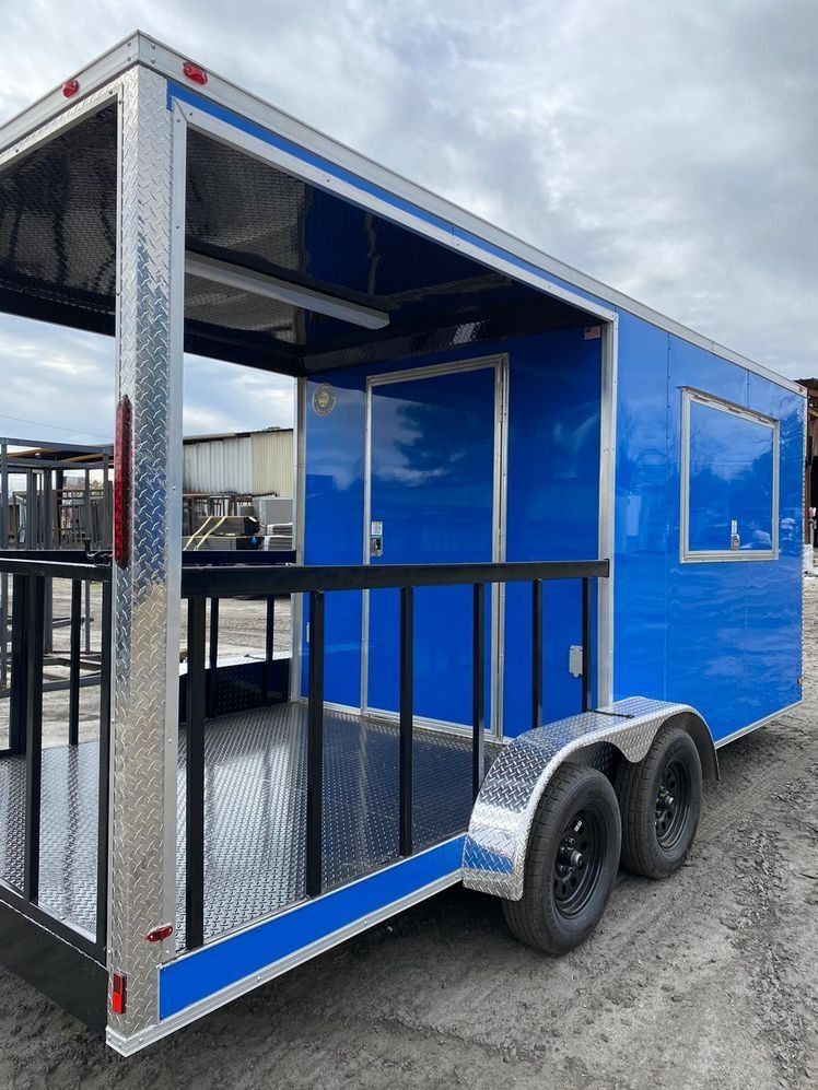 Blue and silver custom enclosed trailer with open back, black tires, and small window.