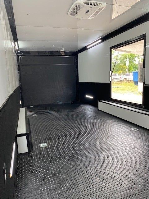 Interior of a black and white cargo trailer with a diamond plate floor and an air conditioner.