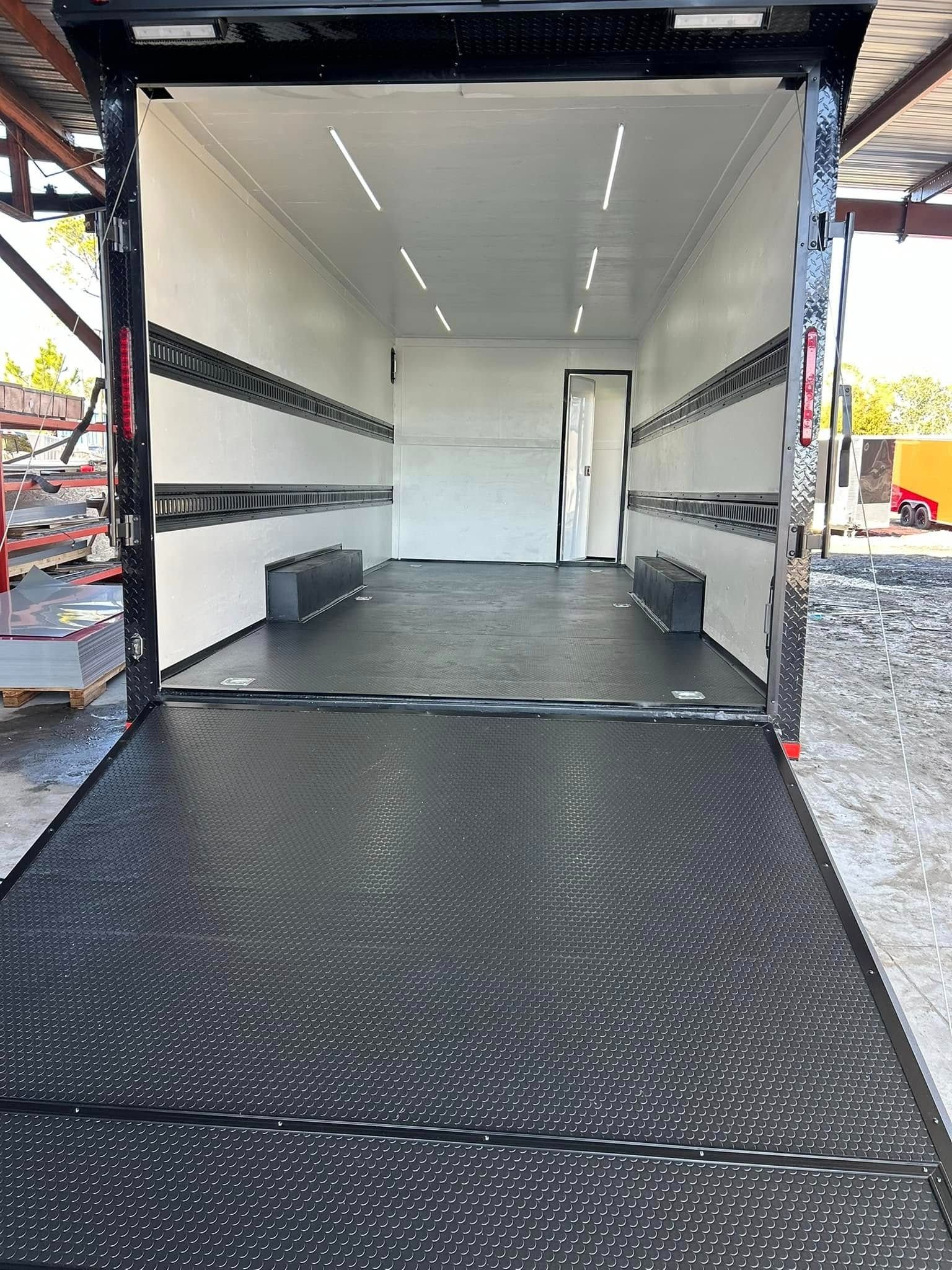 Empty black and white race car trailer interior with ramp open.