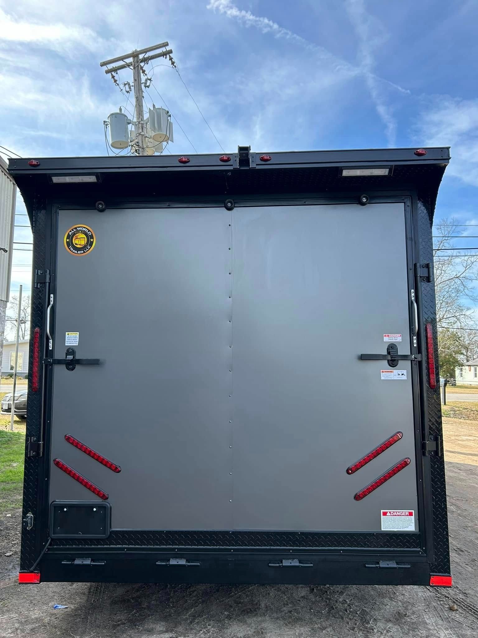 Black cargo trailer with a closed gray door, against a blue sky.