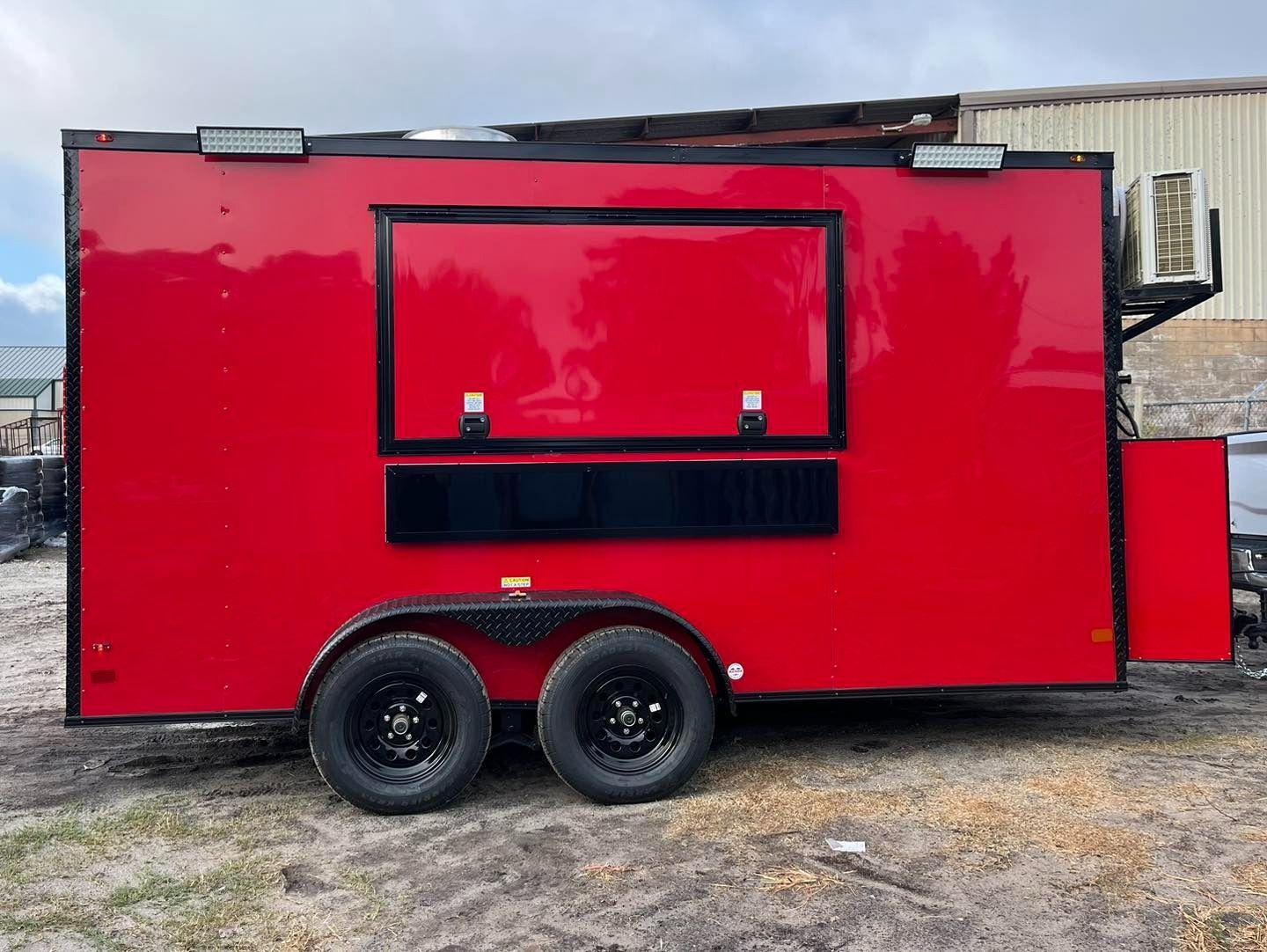 Red food trailer with black accents and two wheels.