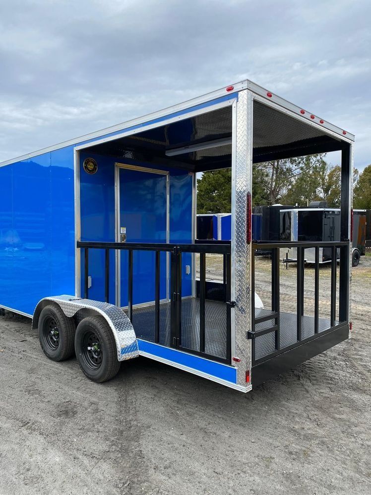 Blue enclosed trailer with a black deck and railings, parked outdoors.