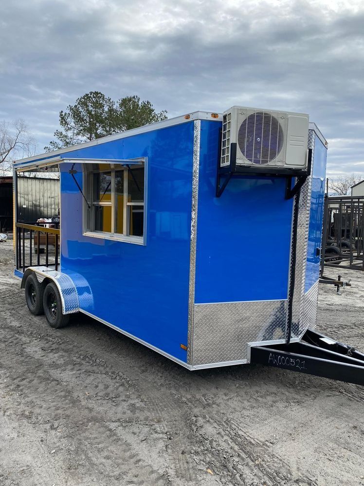 Blue food trailer with a serving window and air conditioning unit.
