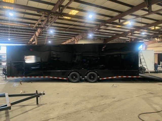 Black enclosed trailer parked inside a warehouse.