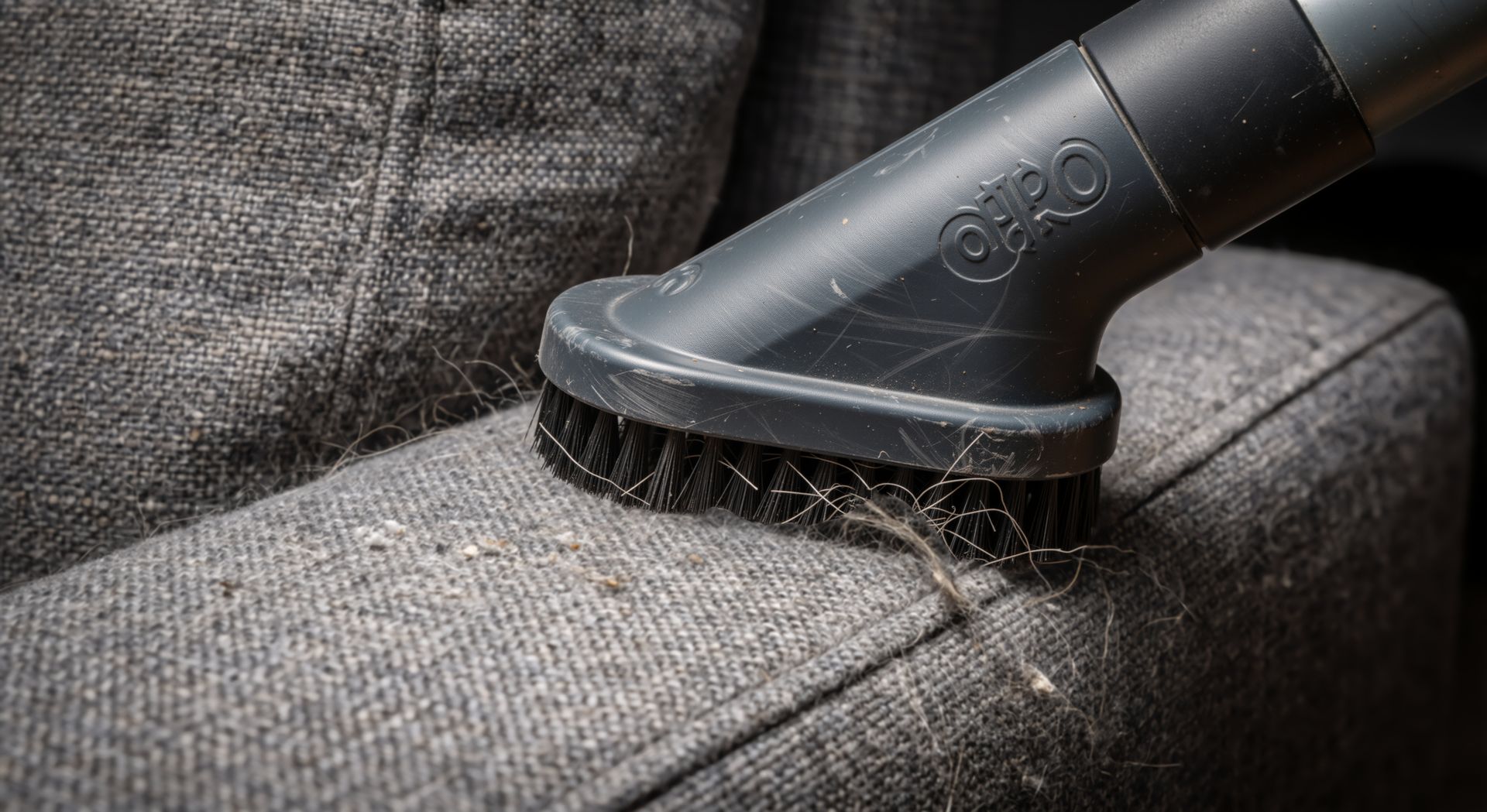 Vacuum cleaner nozzle cleaning gray fabric couch upholstery