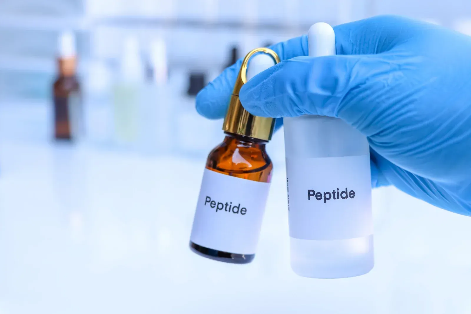 A gloved hand holding two vials labeled