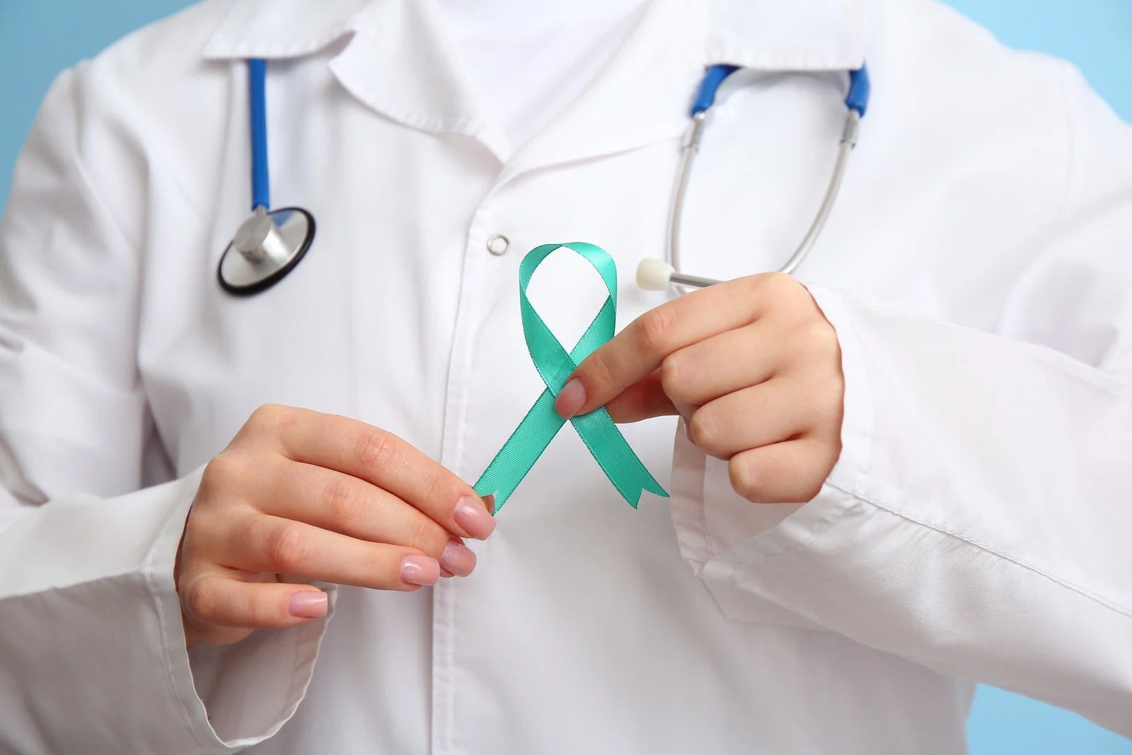 Doctor holding teal awareness ribbon; stethoscope in background.