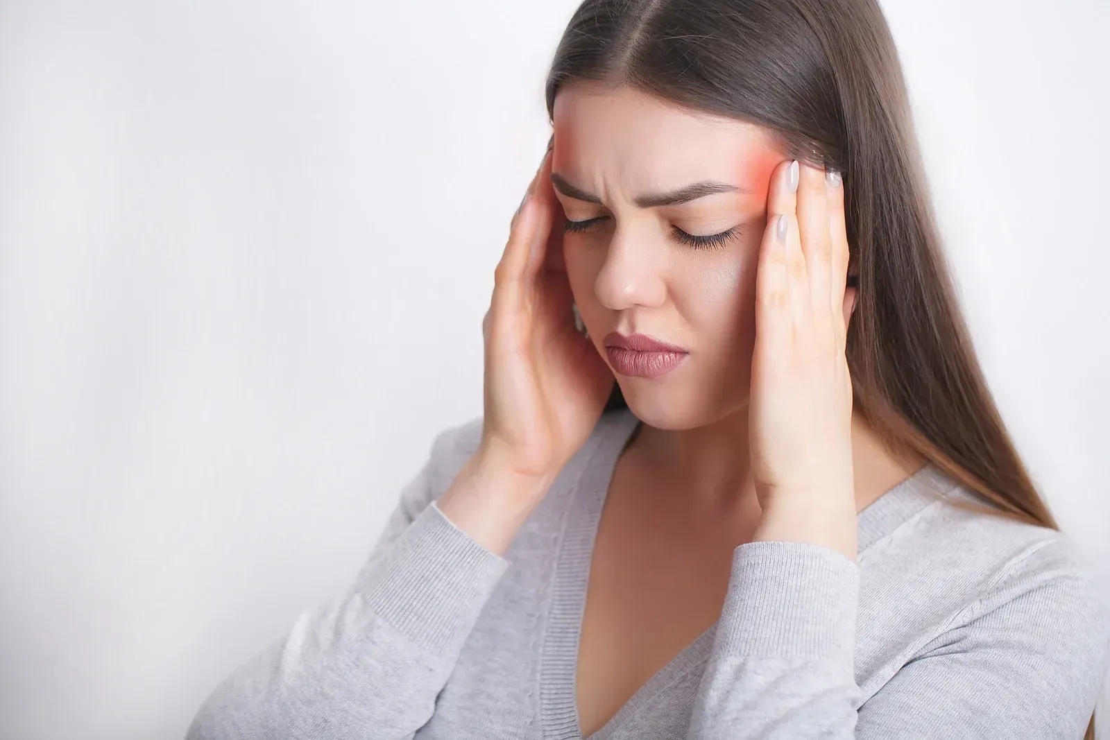 A woman is holding her head in pain because of a headache.