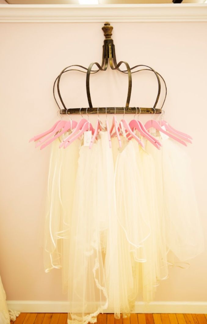 A tutu is hanging on a crown shaped rack with pink hangers.