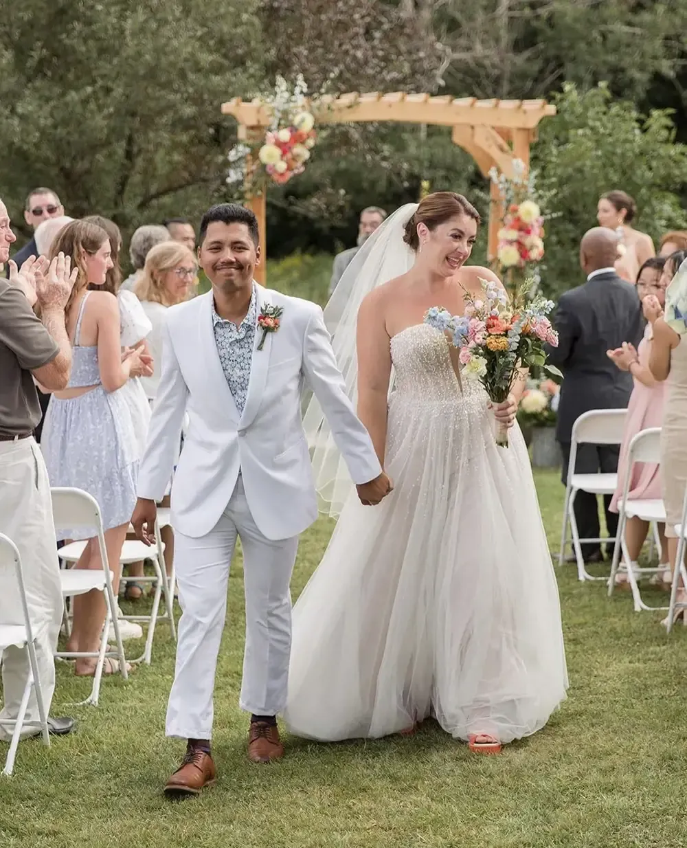 A bride and groom are walking down the aisle at their wedding holding hands.