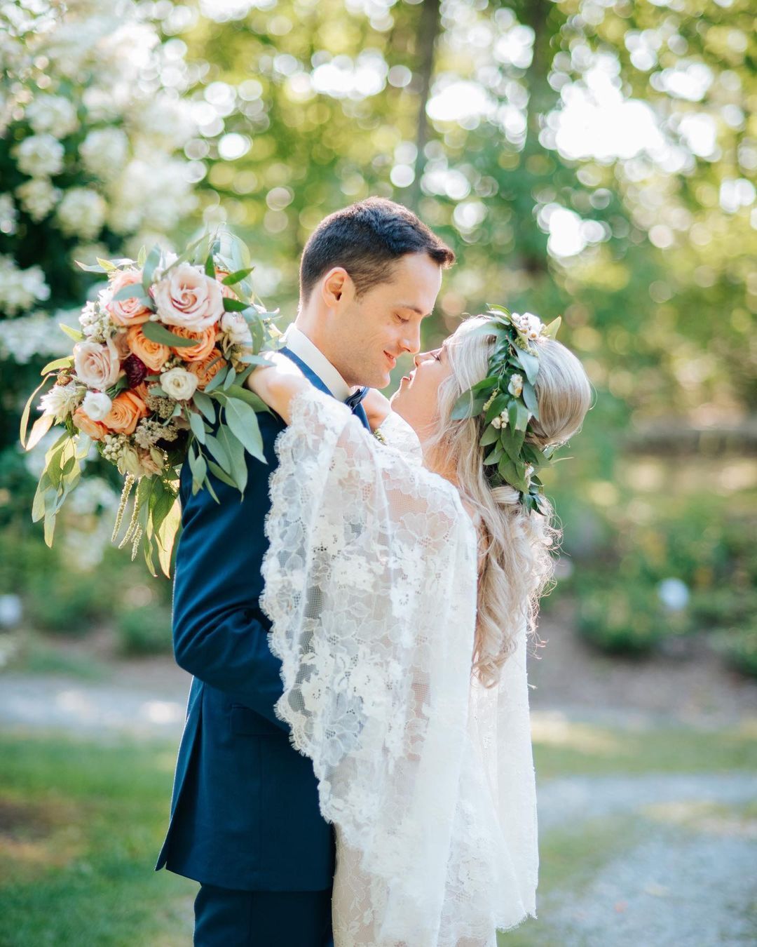 A bride and groom are kissing while the bride is holding a bouquet of flowers.