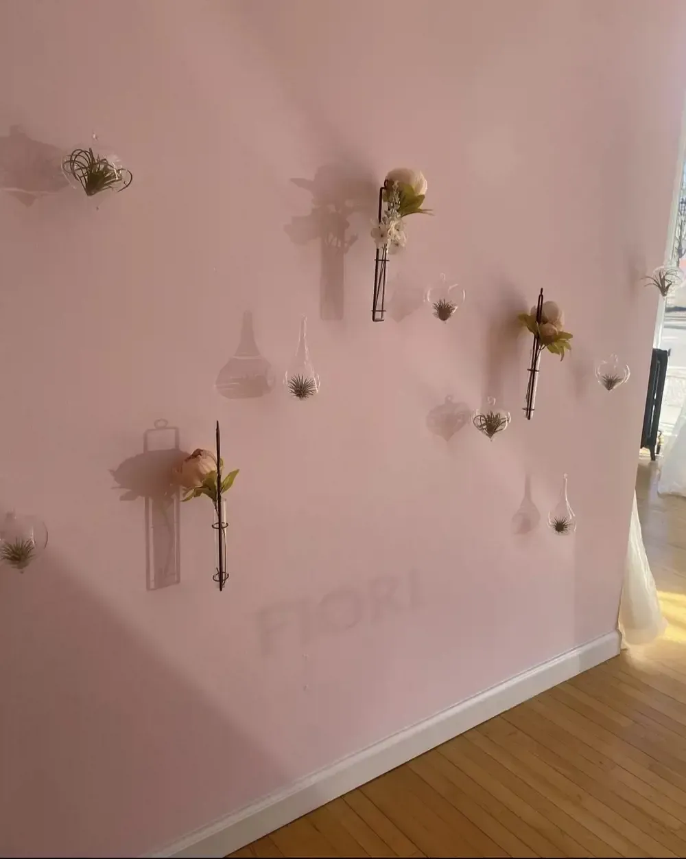 A pink wall with flowers in vases on it.