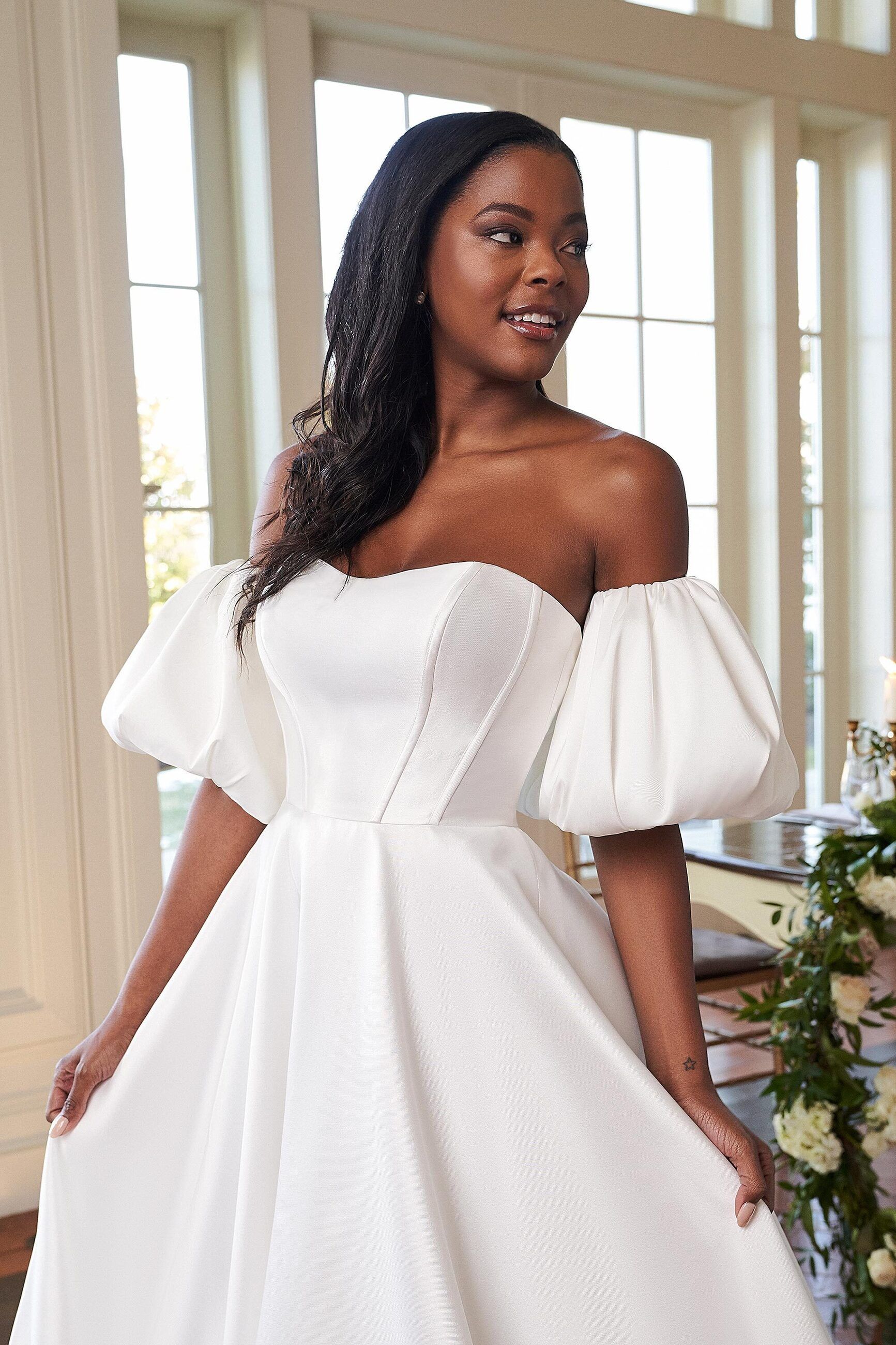 A woman is wearing a white wedding dress with puffed sleeves.