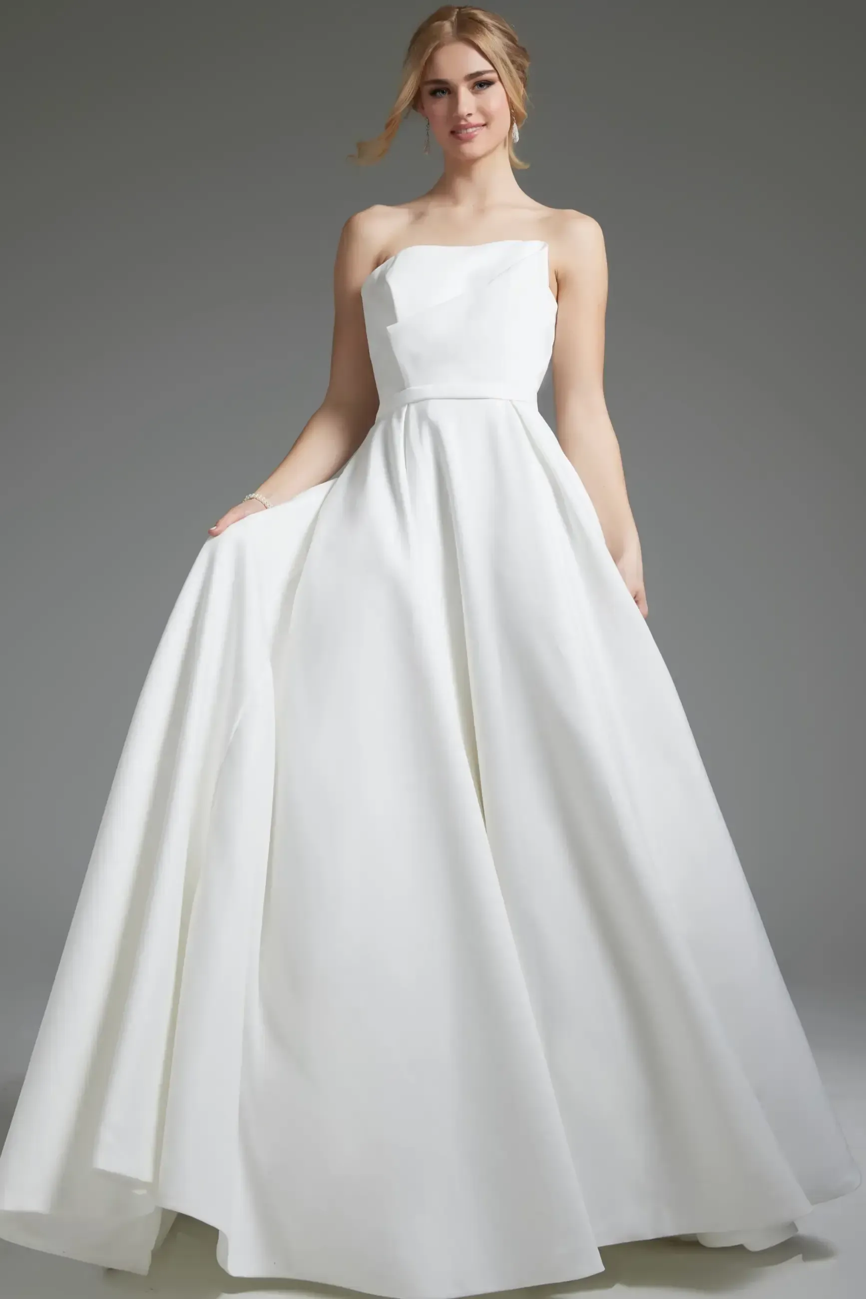 A woman is wearing a white strapless wedding dress.