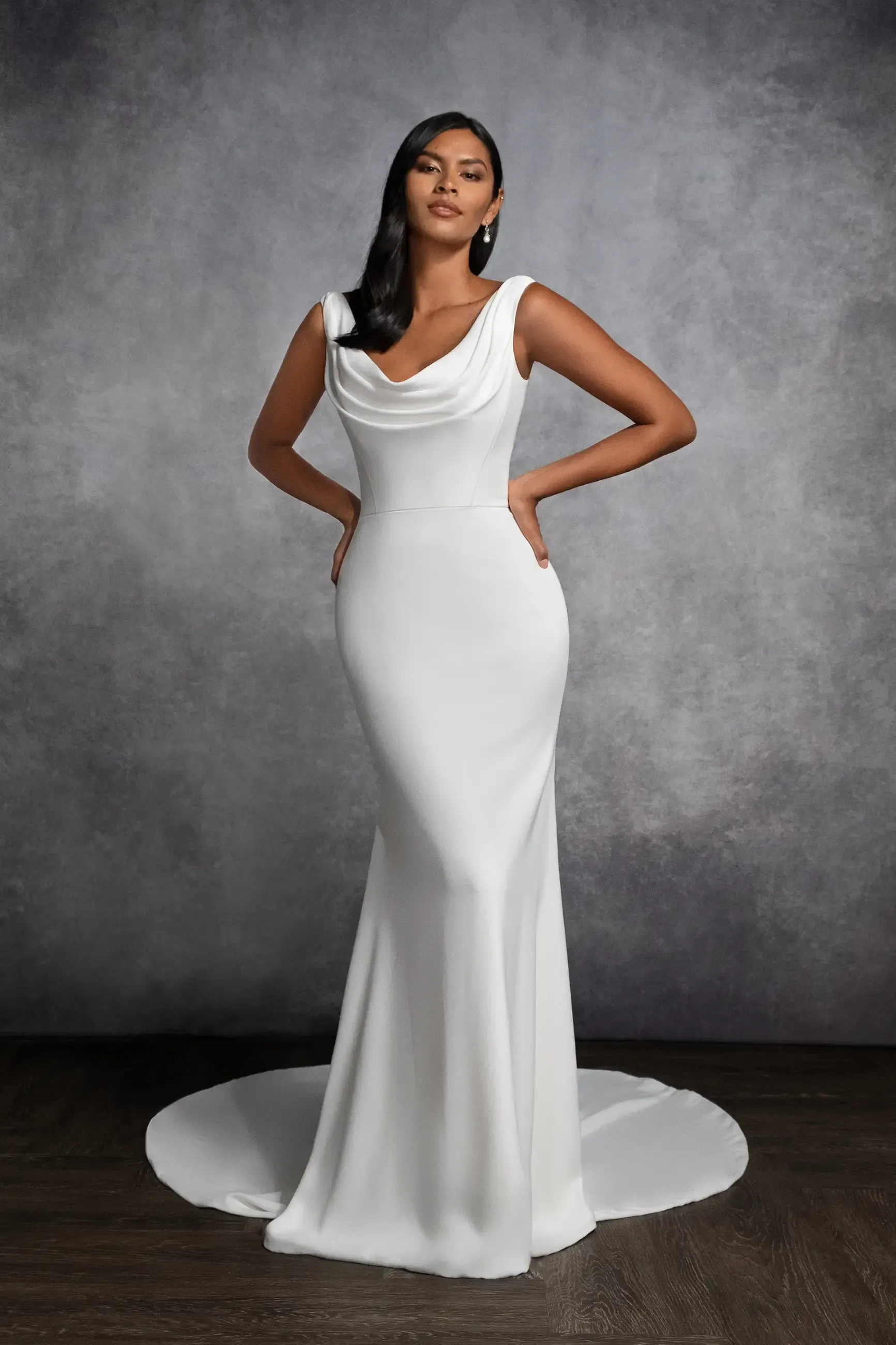 A woman is wearing a white wedding dress with a cowl neckline.