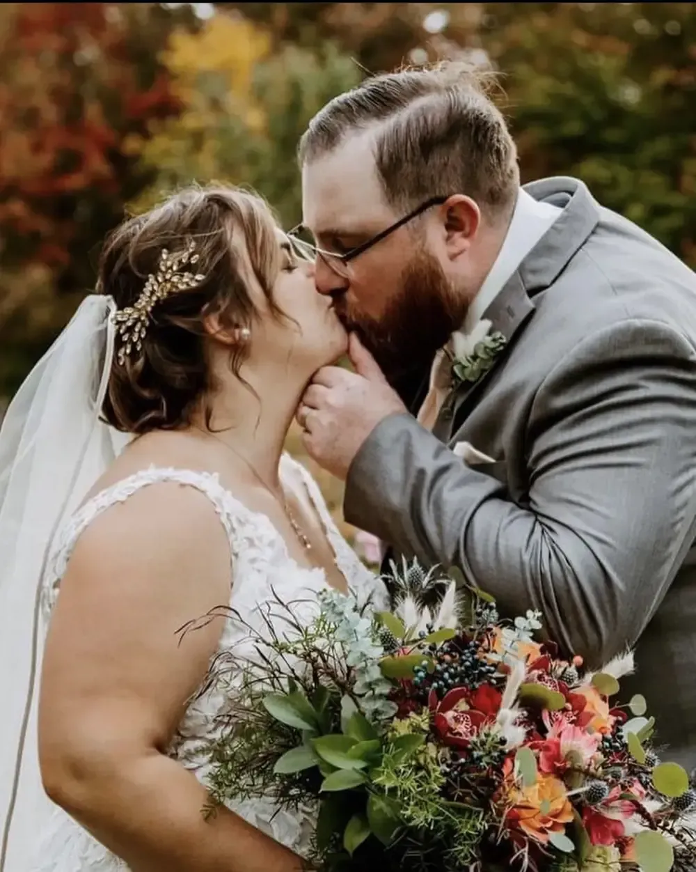 A bride and groom kissing while holding a bouquet of flowers.