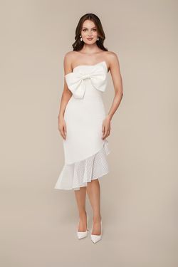 A woman is wearing a white dress with a bow on the front.