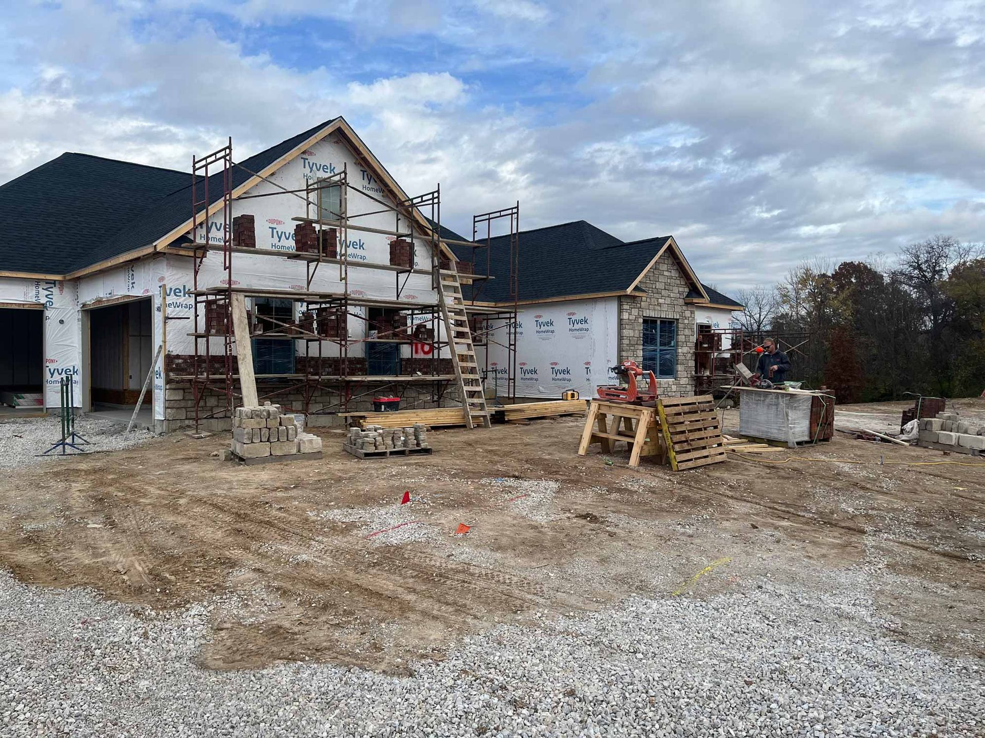 A large house is being built in a dirt field.