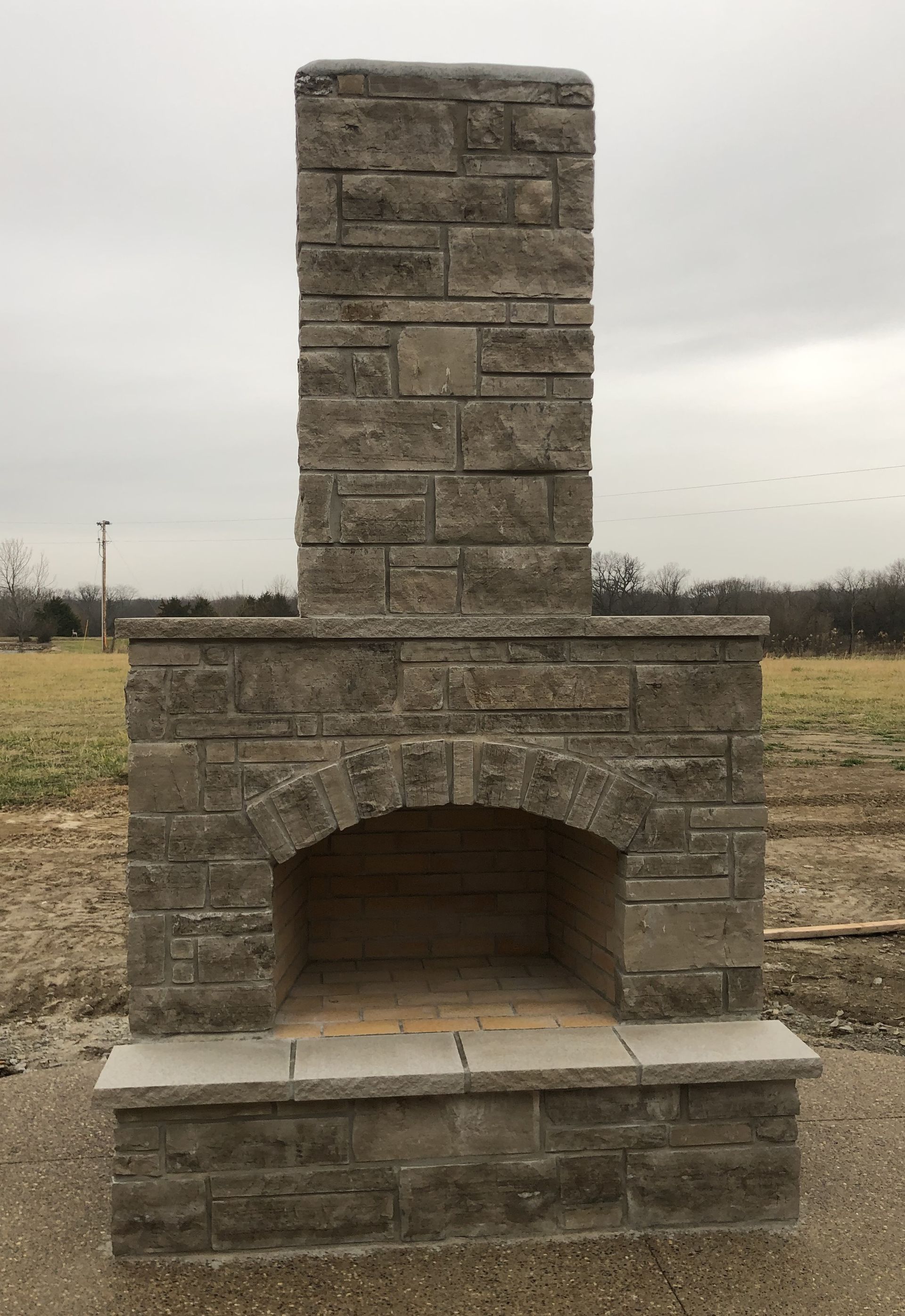A brick fireplace surrounded by logs in a living room