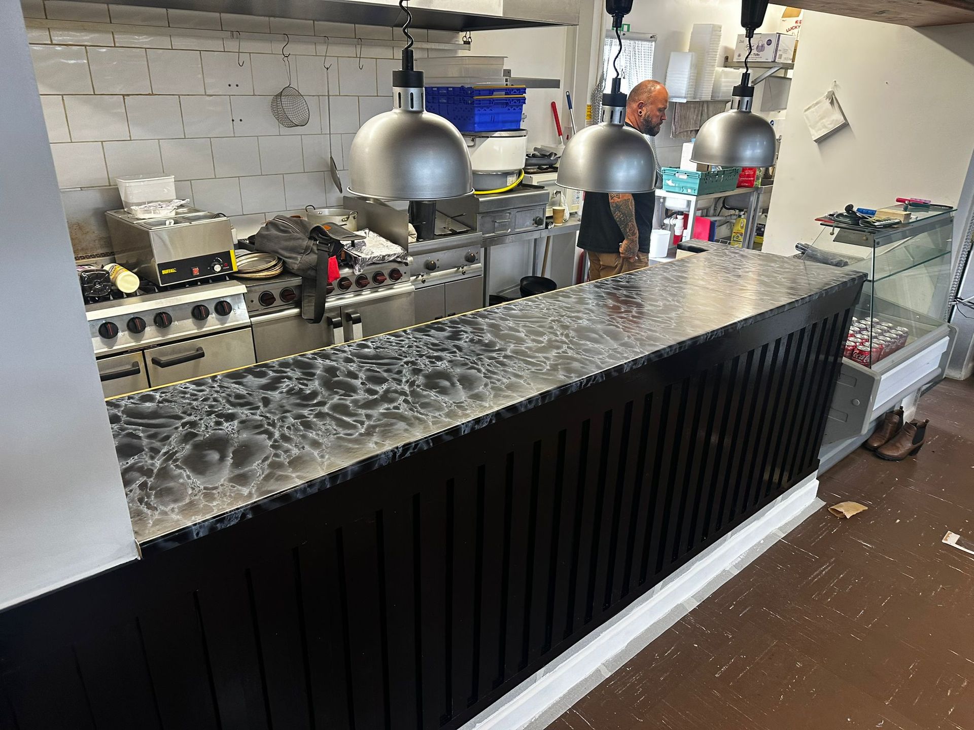 A man is standing behind a counter in a kitchen.