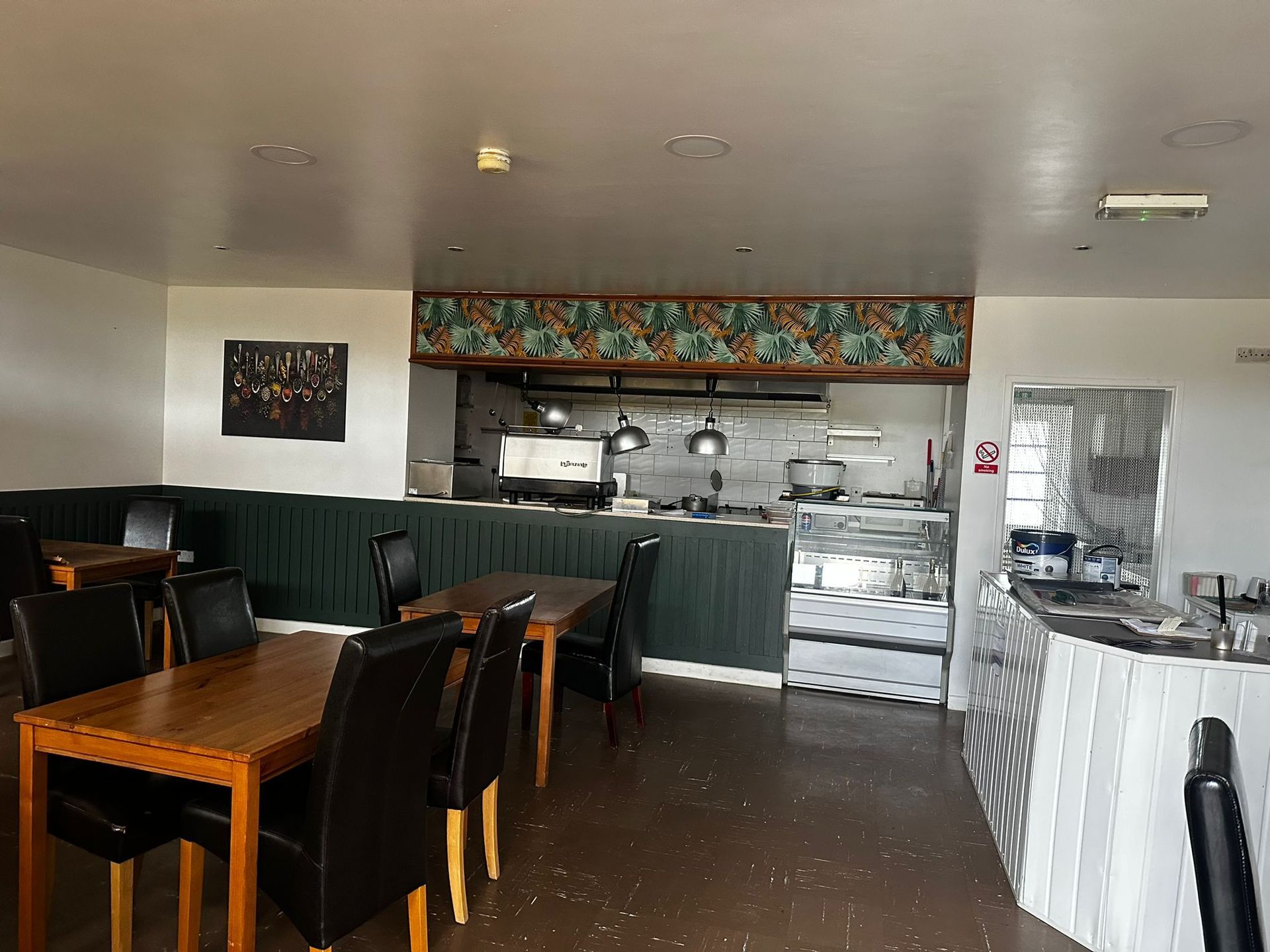 A restaurant with tables and chairs and a kitchen in the background.