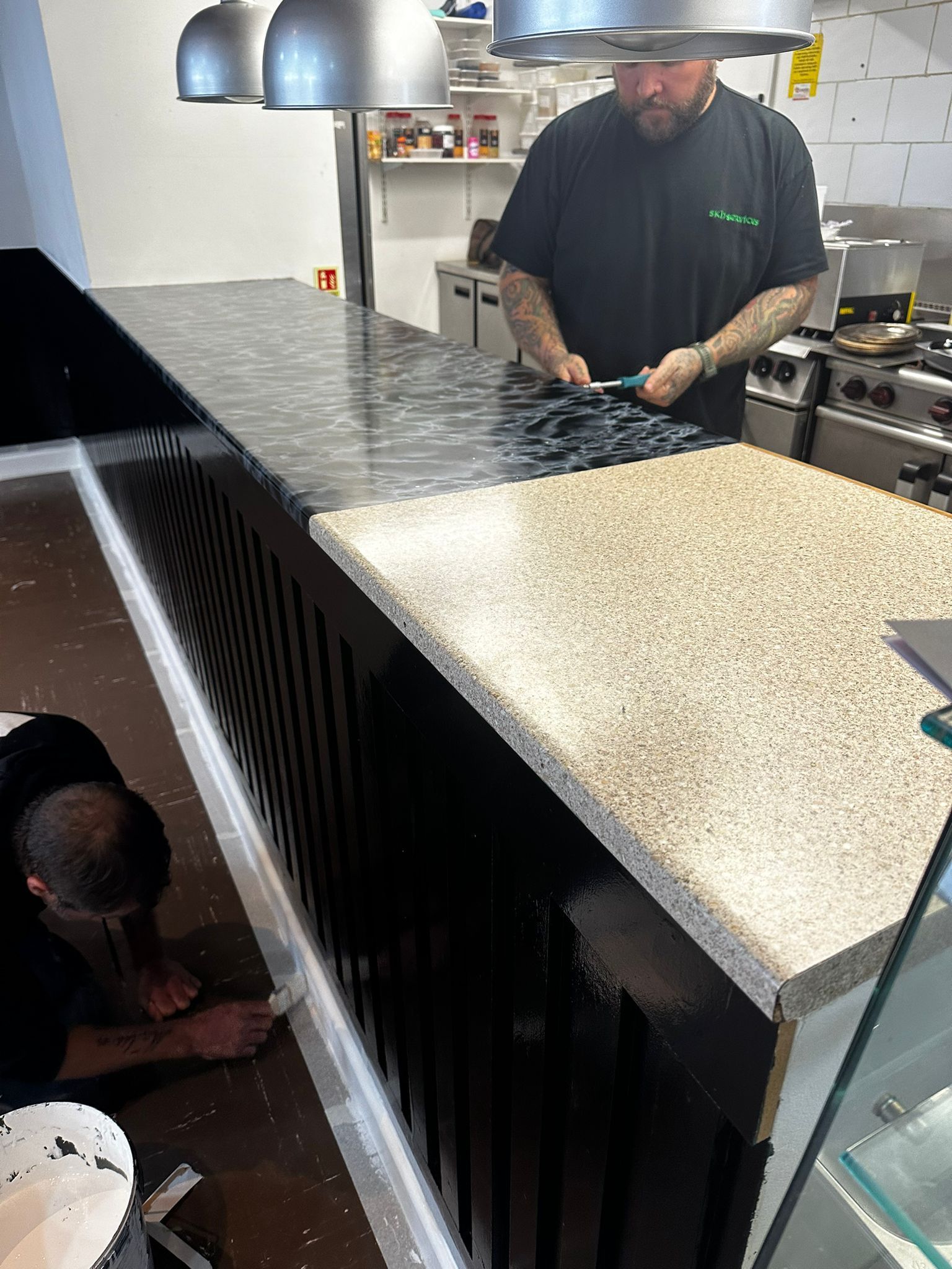 A man is painting a counter top in a kitchen.