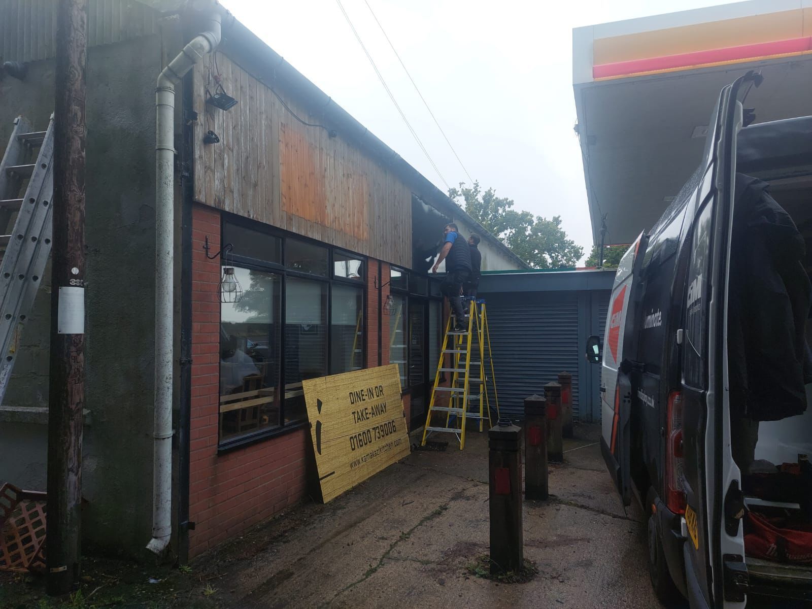 A man is standing on a ladder in front of a building.