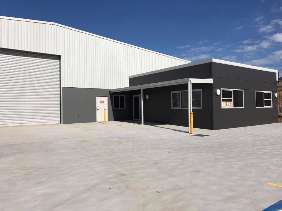 Industrial building with gray and white facade and attached office space under a blue sky. — Easy Mix Concrete In Berkeley Vale, NSW