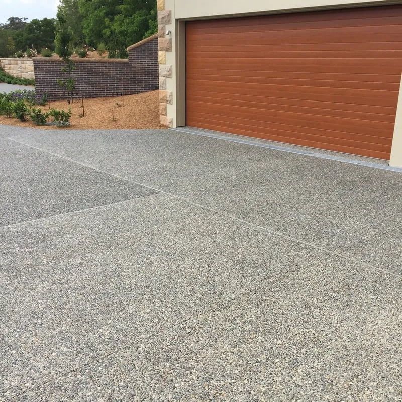 Gray Aggregate Concrete Driveway Leading to a Garage — Easy Mix Concrete In Berkeley Vale, NSW