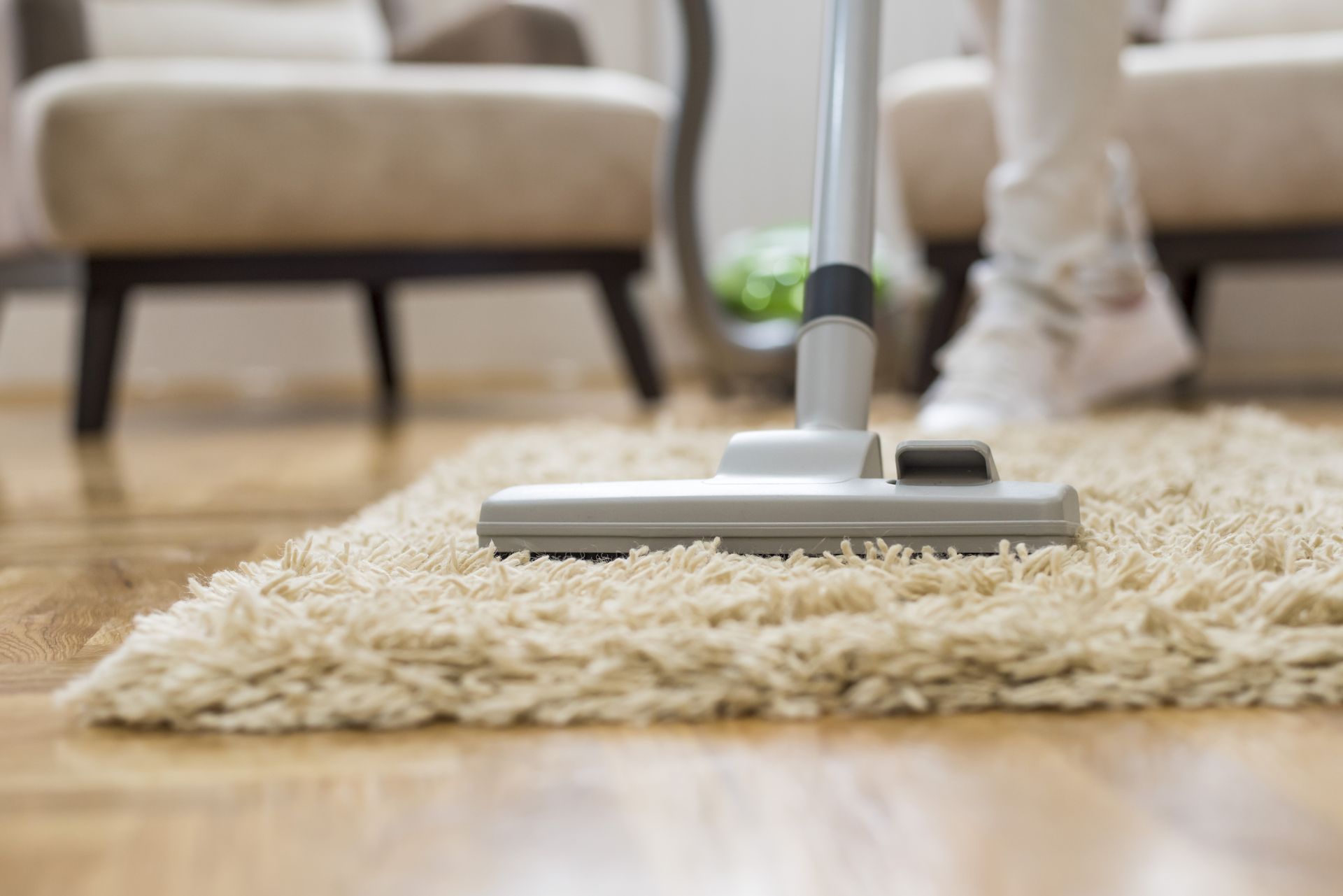 A person is using a vacuum cleaner to clean a rug in a living room.